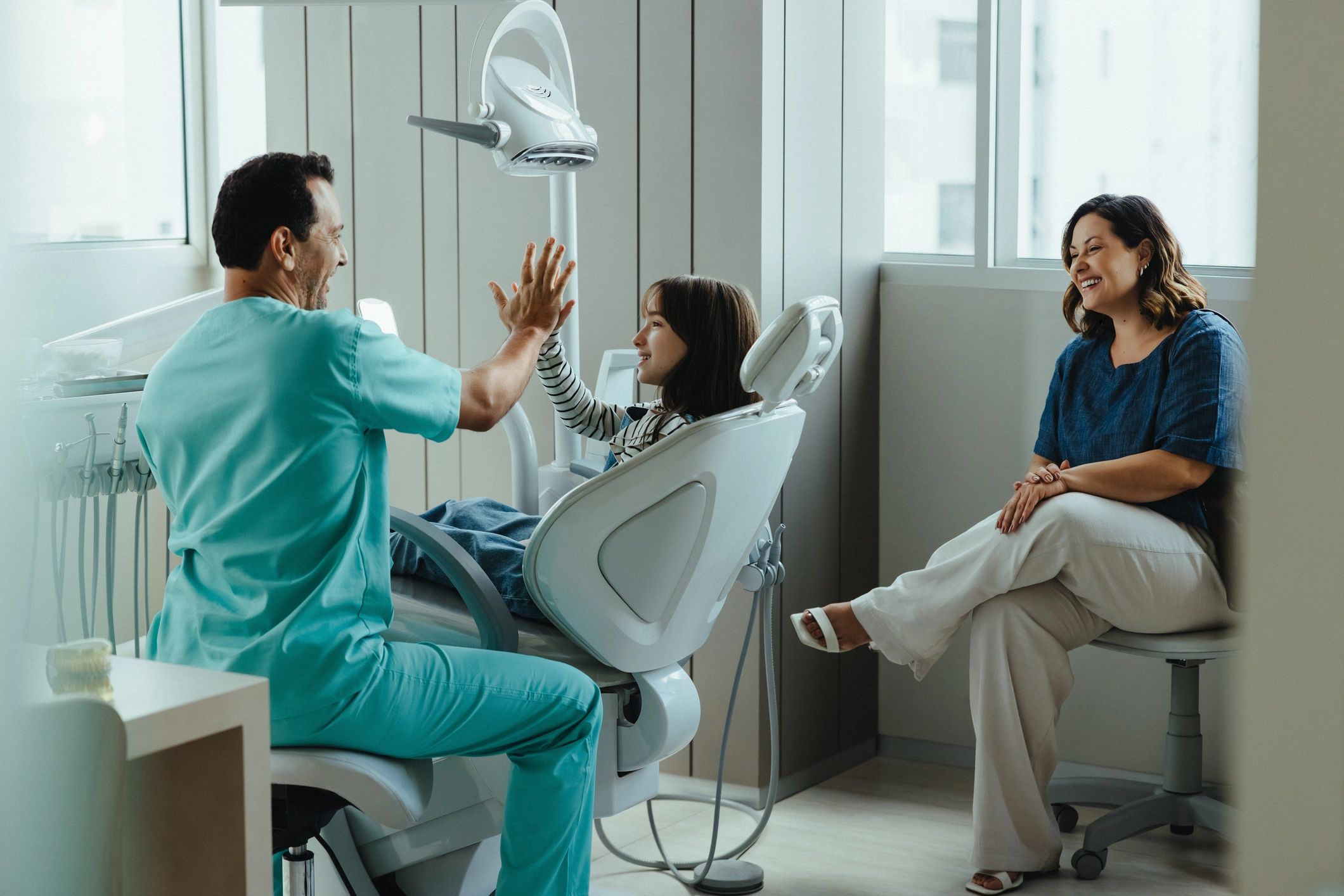 Dentist celebrating a positive visit with a young patient and parent
